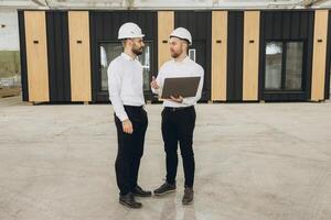 Engineers discussing a project with laptop in a modular building factory photo