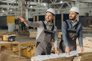 Engineers discussing building project using blueprint in modular house factory photo