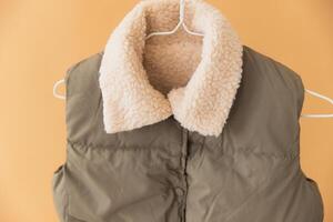 Sleeveless padded jacket with sheepskin lining hanging on hanger photo