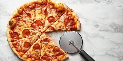 Gluten-free pizza crust being sliced with a pizza cutter on a flat surface, culinary photography photo