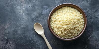 Couscous in a deep, round bowl with a plain spoon beside it, food photography photo