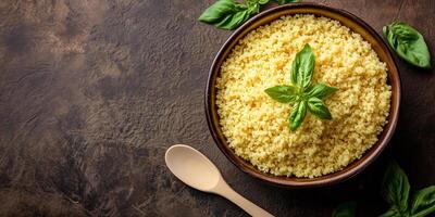 Top-down view of couscous in a deep, round bowl with a utensil beside it, culinary photography photo