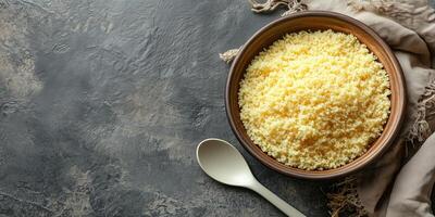 Couscous in a deep, round bowl with a plain spoon beside it, photorealistic food photo