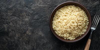 Quinoa arranged in a deep ceramic bowl, with visible grains and a basic fork beside it, meal photography photo
