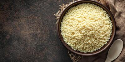 Couscous in a deep, round bowl with a plain spoon beside it, meal photography photo