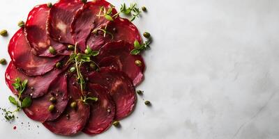 Bresaola slices arranged in a circular pattern with capers scattered on top, food setting photo