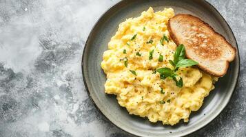 Scrambled eggs on a plate with a small serving of toast beside it, food setting photo