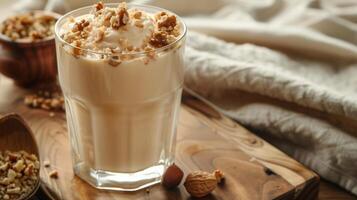 Thick, beige liquid in a glass, topped with crushed nuts, displayed on a wooden board, gastronomy photography photo