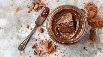 Top-down view of open jar of chocolate spread next to spreading knife, photorealistic food photo