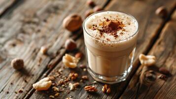 Frothy liquid in a glass, surrounded by a few scattered nut pieces on a wooden table, food setting photo