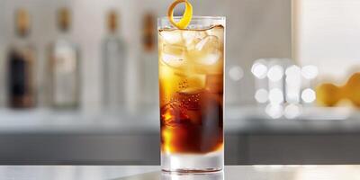 Tall glass with layers of clear and brown liquids, garnished with a lemon twist, food setting photo
