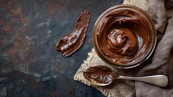 Open jar of chocolate spread with a spoonful scooped out, placed beside a napkin, meal photography photo