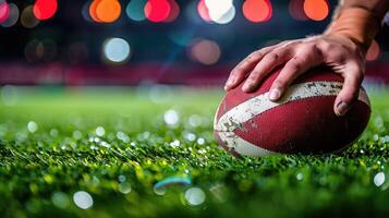 Rugby player's hand holding a rugby ball on the field photo
