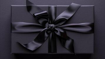Black gift box with black ribbon and bow on a dark background photo
