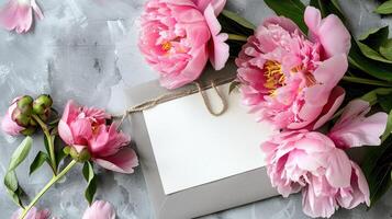Pink peonies flowers and envelope on a gray background photo