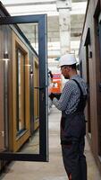 operaio nel uniforme installazione plastica finestre nel prefabbricato componibile Casa. verticale video