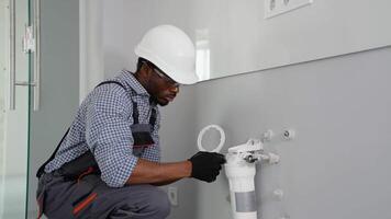 African plumber installs or change water filter. Installation of reverse osmosis water purification system video