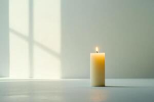 A Single Candle Burning in the Light of a Window photo