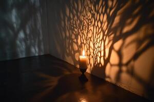 A Single Lit Candle Casting a Tree-Like Shadow on a Wall photo