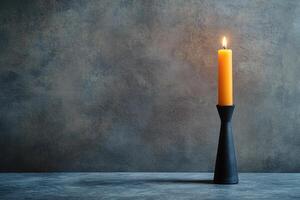 A Single Burning Candle in a Black Holder on a Grey Surface photo