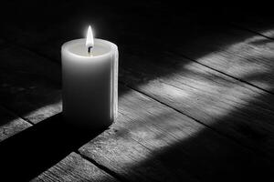 A Single Candle Burning on a Dark Wooden Surface photo