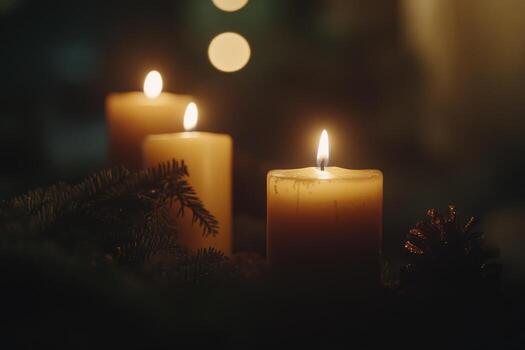 Three Lit Candles Among Evergreen Branches and a Pine Cone photo