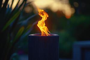 A Single Flame Burning in a Black Cylinder at Sunset photo