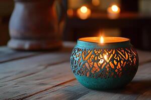 Teal Candle Holder with Ornate Design Glowing on a Wooden Table photo