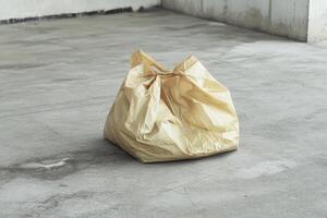 A Crumpled Yellow Plastic Bag on a Concrete Floor photo