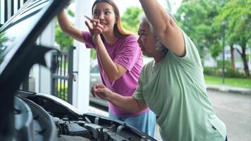 Grandmother and grandchild help each other execute a basic engine check on their parents' automobile photo