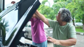 Grandmother and grandchild help each other execute a basic engine check on their parents' automobile photo