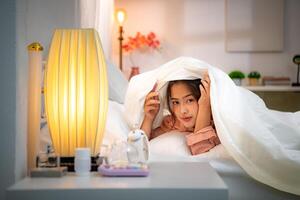 Asian young woman on the bed in the bedroom trying to wake up and prepare for work photo