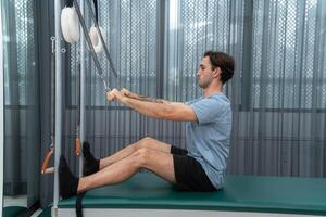 A young man doing pilates exercises on a pilates cadillac photo