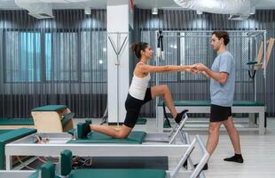 A young man and a young woman are doing pilates exercises on a pilates reformer photo