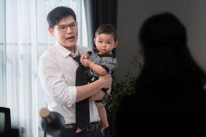 A business father assigns work to his secretary, while also taking care of his child while working photo