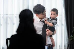 A business father assigns work to his secretary, while also taking care of his child while working photo