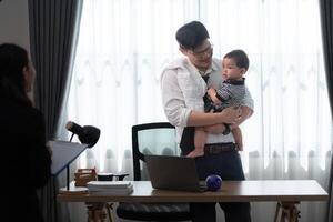 A business father assigns work to his secretary, while also taking care of his child while working photo