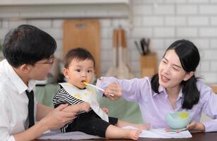 Father and mother feed their son breakfast before going to work in the kitchen of the house photo
