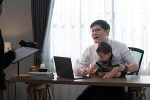 A business father assigns work to his secretary, while also taking care of his child while working photo