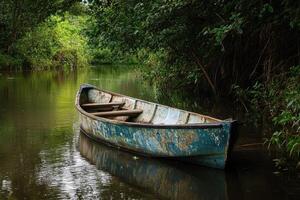 A weathered wooden rowboat rests in a still river, surrounded by lush green foliage. photo