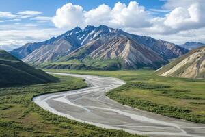 A winding river flows through a valley surrounded by snow-capped mountains. photo