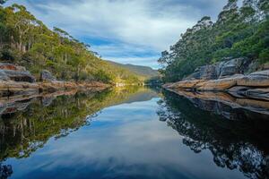 Tranquil River Reflecting Lush Green Foliage and a Cloudy Sky photo