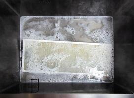 kitchen hood filters for sinks with a modern oxygen cleaner for grease and stains. Washing and cleaning the kitchen, close-up. Chemical reaction photo