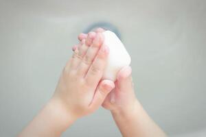 A child washes his hands with soap in the bathroom. The concept of hygiene and clean hands, infection, close-up, soundness photo