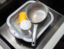 Dirty dishes in a sink basin with hot water and foam from an environmental oxygen cleaner. A modern product for removing dirt and stains. photo