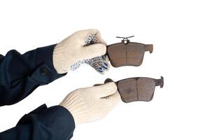 An auto mechanic holds in his hands old worn out brake pads on a white background, isolate. The concept of replacing brake pads with new ones photo