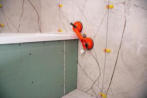 Laying large-format porcelain tiles with a suction cup in the bathroom. Copy space for text. Tile leveling system photo