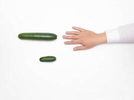Male hand on a white background reaching for a big cucumber, the concept of increasing the male penis using different techniques, medical, copy space, erection photo