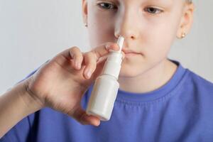 A caucasian girl puts drops into her nose and an anti-inflammatory spray for nasal congestion. Treatment of runny nose and sinusitis. Antibiotic medicinal spray, close-up photo