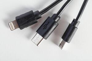 Universal black 3 in 1 charging cable with different charging connectors on a white background, close-up. Type-c, usb-c, micro-usb photo